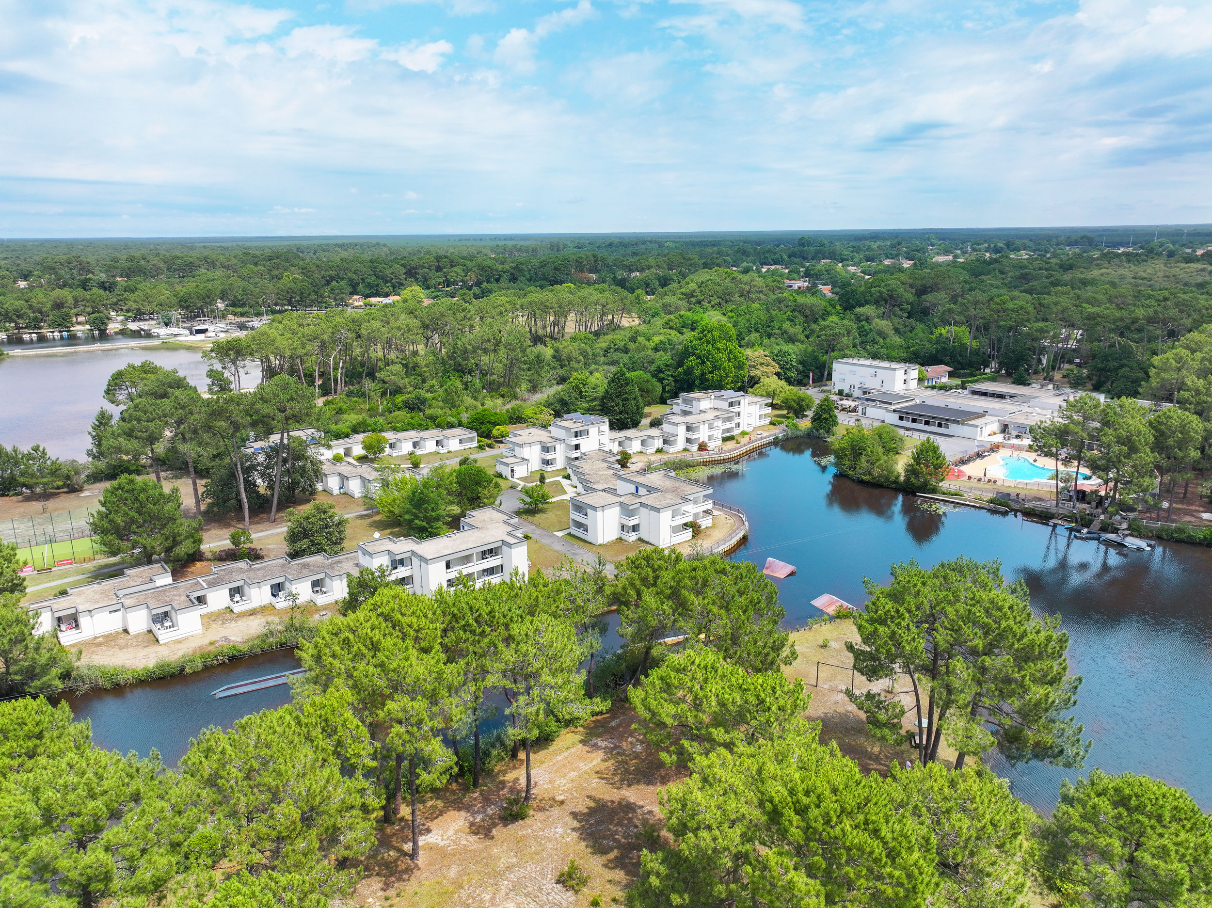 Vue aérienne d'une résidence de vacances en bord de lac, entourée de verdure et avec une piscine visible