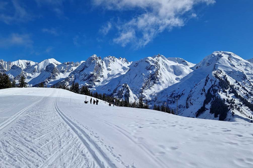 Piste enneigée à La Clusaz avec vue sur les montagnes du massif des Aravis en Haute-Savoie