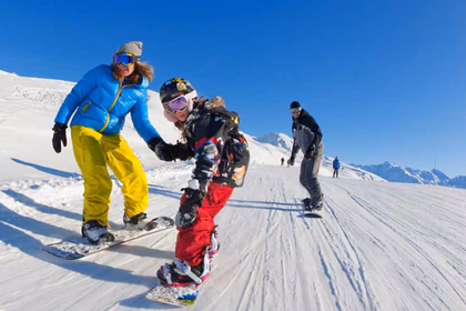 Famille avec enfants pratiquant le snowboard sur les pistes de ski