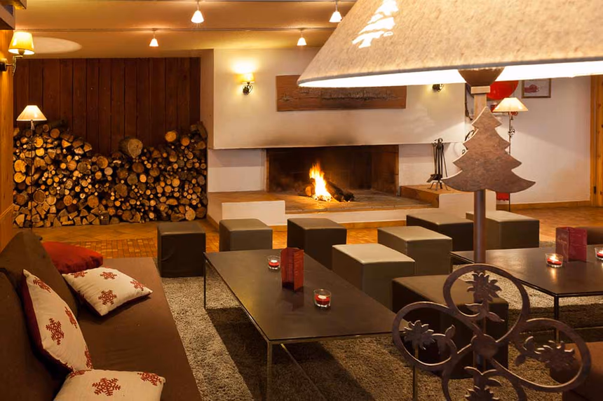 Salon cosy avec grande cheminée allumée, décoration montagnarde et atmosphère chaleureuse pour l'après-ski