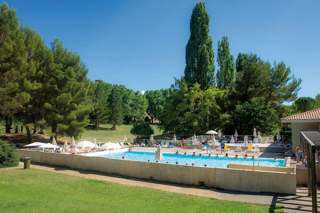 Piscine extérieure d'un Village Vacances Azureva entourée de pelouse, de cyprès et de pins, avec familles se baignant sous le soleil