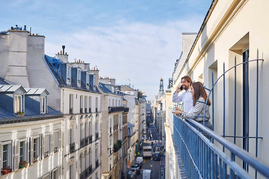 Couple profitant d'un moment sur le balcon d'un hôtel Azureva à Paris avec vue sur les toits haussmanniens et la Tour Eiffel en arrière-plan