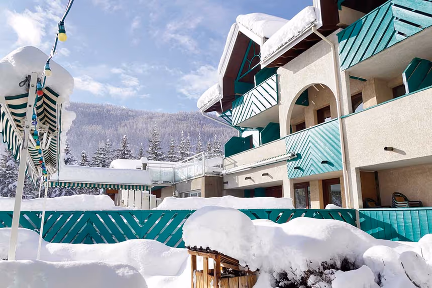 Façade enneigée d’un village vacances Azureva à la montagne avec chalets, balcons verts et paysage alpin