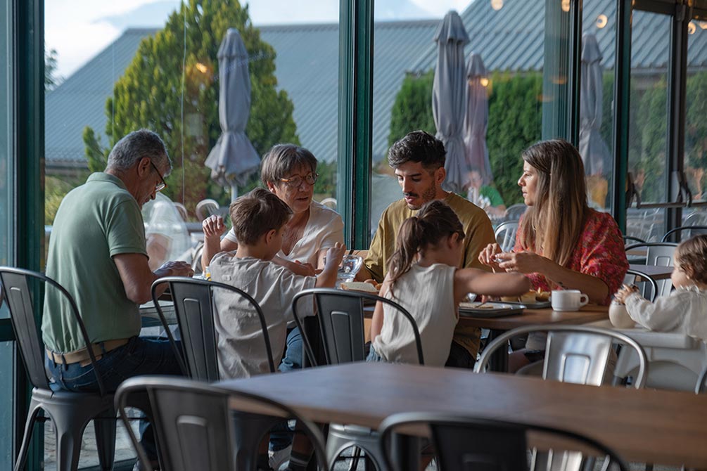 Famille réunie autour d’un repas convivial dans un restaurant de village vacances