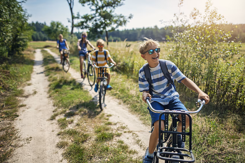 Enfants faisant du vélo sur un chemin de terre entouré de nature près d'une résidence de vacances France.