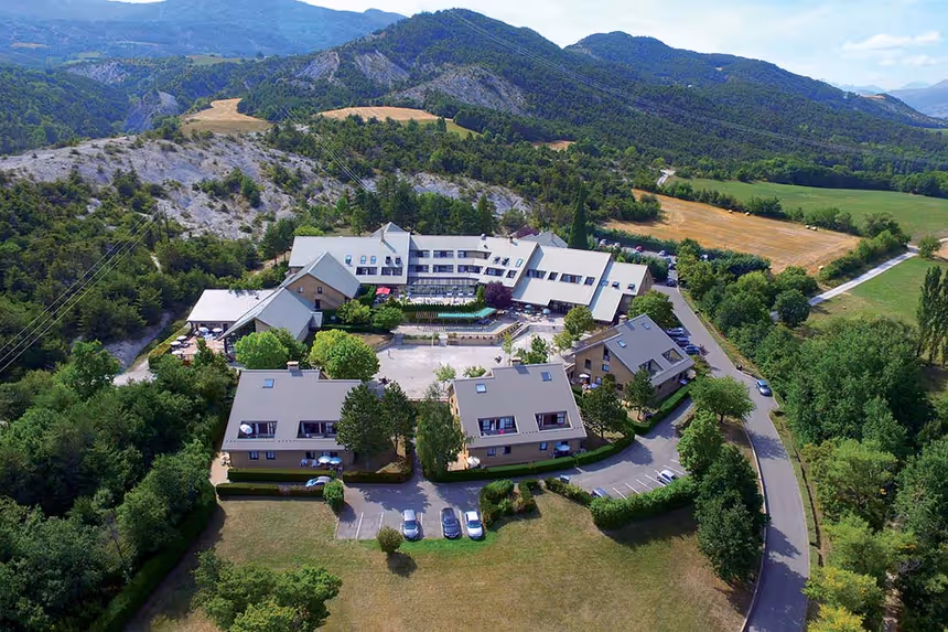Vue aérienne du village vacances dans la Drôme, entouré de nature et montagnes