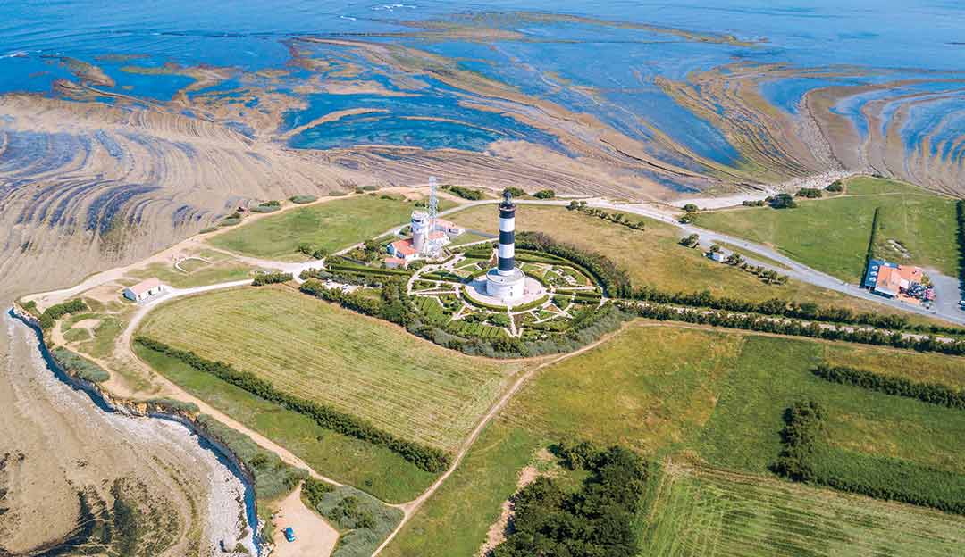 Vue aérienne du phare de Chassiron sur l'Île d'Oléron avec bancs de sable sculptés par la marée et jardins en étoile en Charente-Maritime