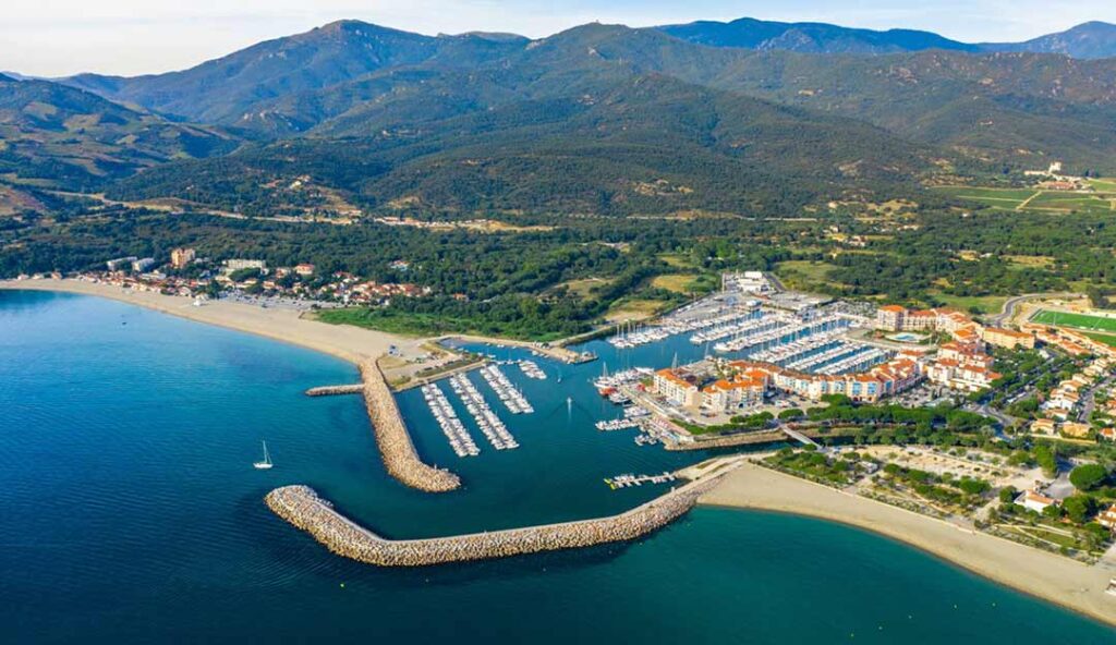 Port de plaisance d'Argelès-sur-Mer avec marina moderne, voiliers et montagnes des Pyrénées en arrière-plan en Occitanie