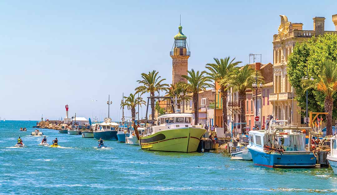Canal du Grau-du-Roi avec phare, bateaux de pêche, jet-skis et activités nautiques en Camargue gardoise, ambiance estivale