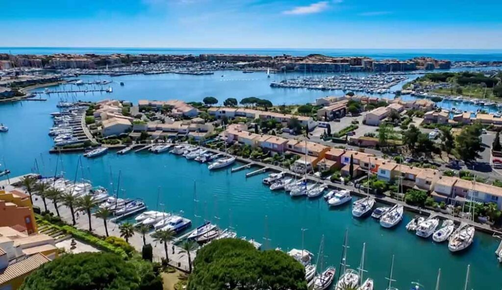 Port de plaisance méditerranéen avec voiliers, marina moderne et maisons colorées au pied des montagnes dans le Sud de la France