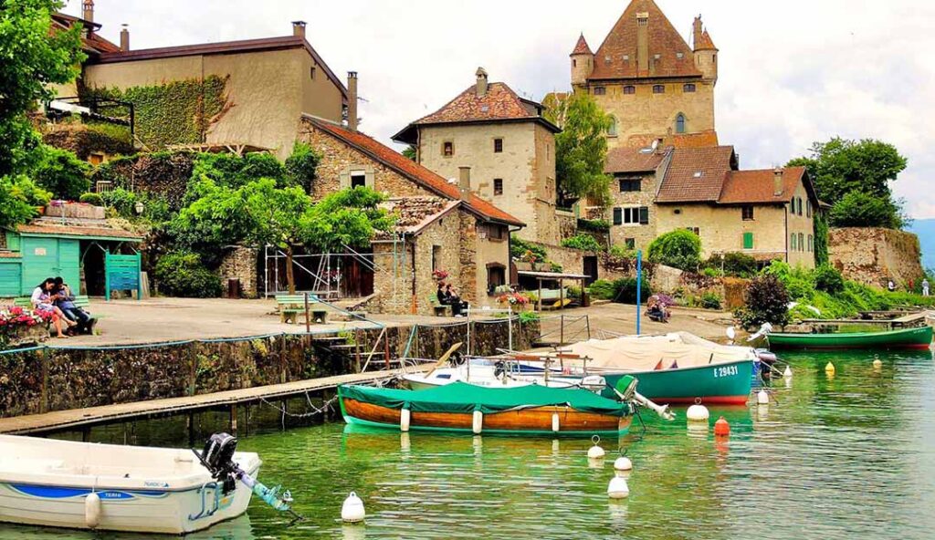Port d’Yvoire avec bateaux amarrés et maisons médiévales au bord du lac Léman